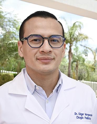 Es la foto de perfil de un cirujano pediátrico en León de Hospital Angeles León. Usa una bata blanca con camisa y usa lentes.