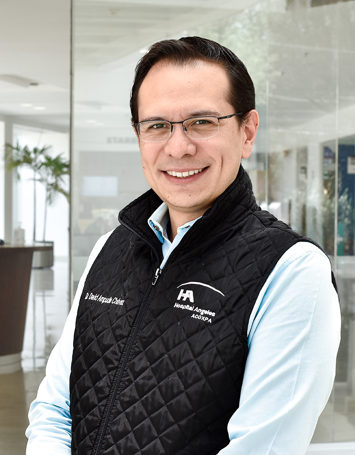Es la foto de perfil de un endoscopista especializado en gastrocirugía y cirugía general en Ciudad de México de Hospital Angeles. Tiene una camisa blanca con un chaleco negro y corbata verde bandera. 