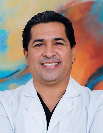 Es la foto de perfil de un cirujano maxilofacial en Tampico de Hospital Angeles Tampico. Usa una bata blanca. Tiene el cabello negro y está sonriendo.