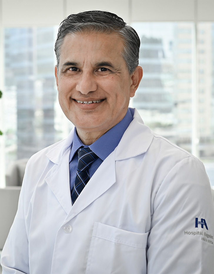 Es la foto de perfil de un pediatra en San Pedro Garza de Hospital Angeles Valle Oriente. Usa una bata blanca, una camisa azul claro y una corbata azul oscuro. Tiene el cabello gris. Está sonriendo.