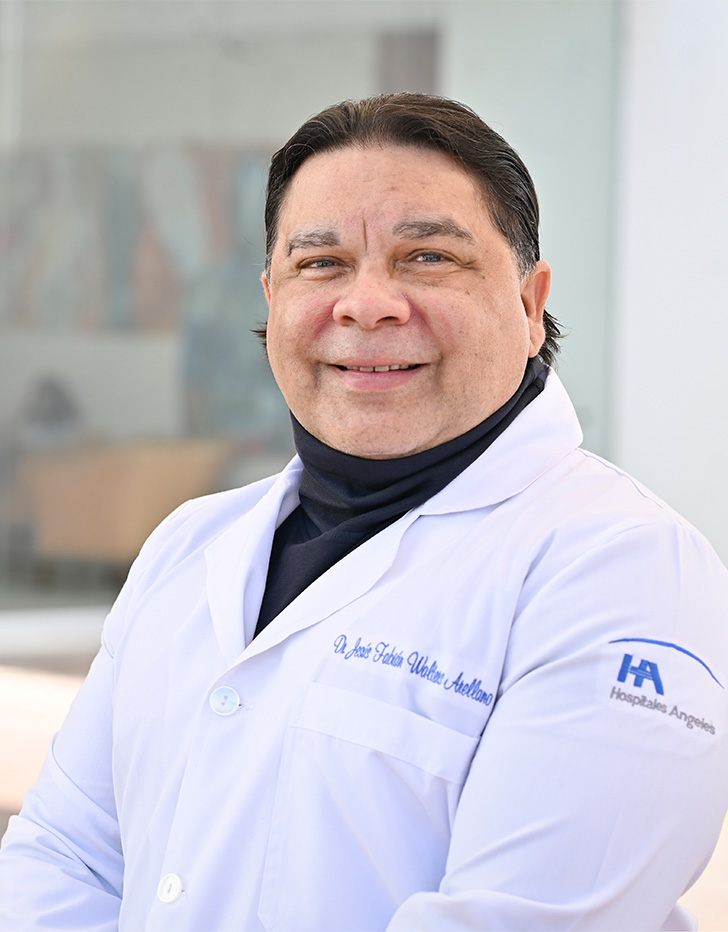 Es la foto de perfil de un ginecólogo y obstetra en Tijuana. Usa una bata con una blusa de cuello alto negra. Tiene el cabello negro y recogido. Está sonriendo.