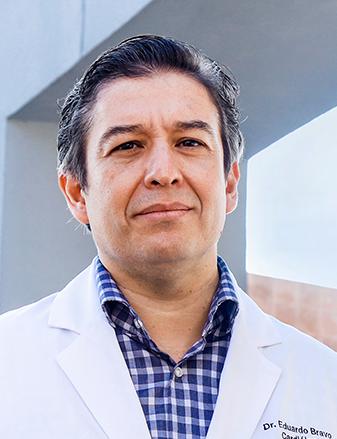 Es la foto de perfil de un cardiólogo intervencionista en Guadalajara de Hospital Angeles Del Carmen. Utiliza una bata blanca, camisa azul marino y cuadros blancos.