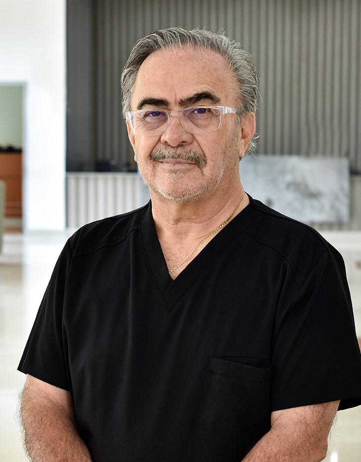Es la foto de perfil de un oftalmólogo en Tampico de Hospital Angeles. Usa un uniforme médico negro. Tiene el cabello gris. Tiene una sonrisa ligera.