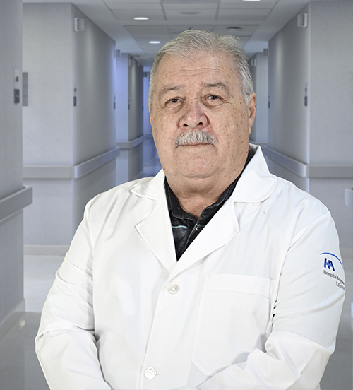 Es la foto de perfil de un psiquiatra en Ciudad Juárez de Hospital Angeles Ciudad Juárez. Utiliza una bata blanca, una camisa lila y tiene bigote y cabello canoso.